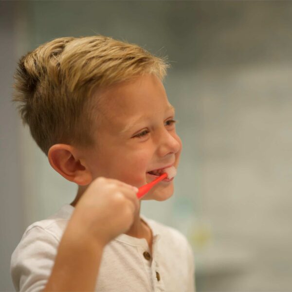 Little Boy Using Brilliant Oral Care Red Round Toothbrush
